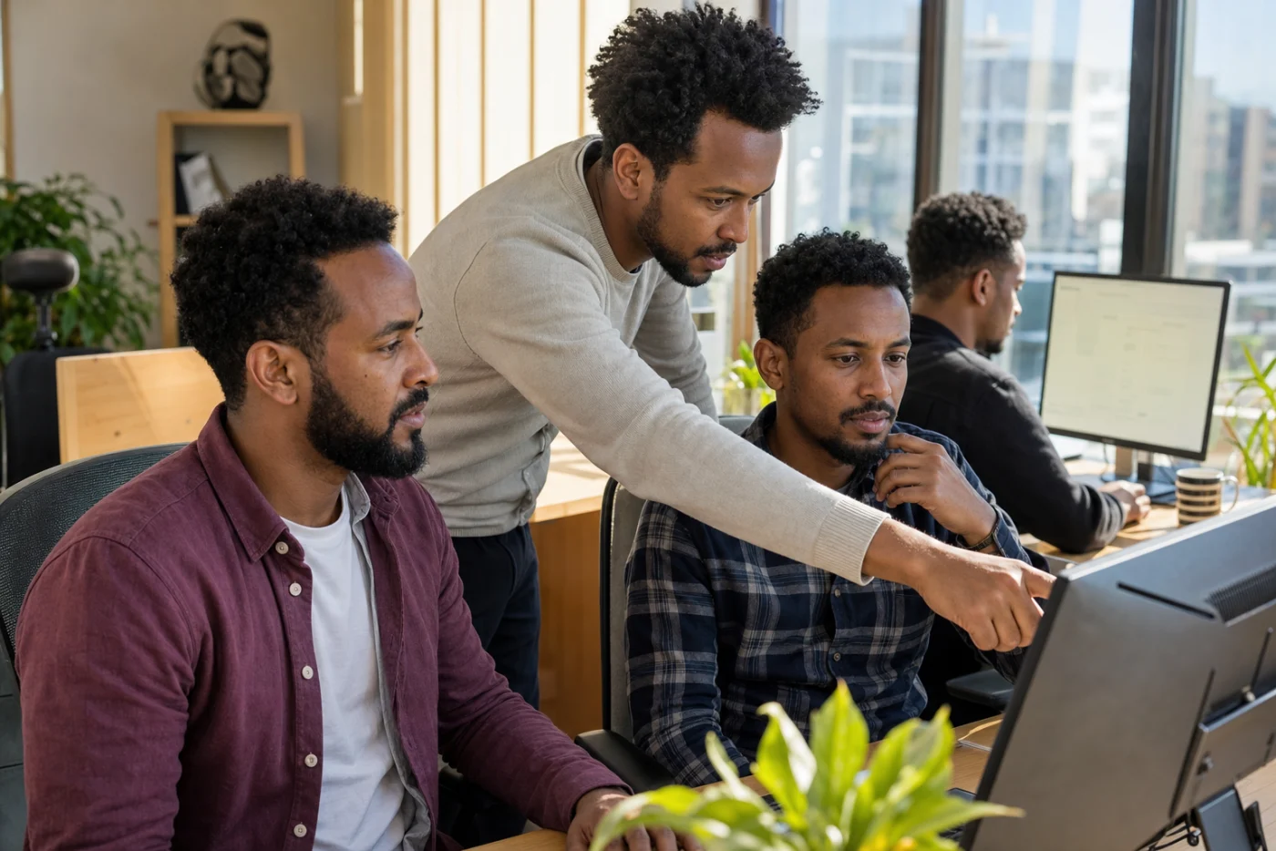 Ethiopian software developers collaborating at a sunny cluster desk